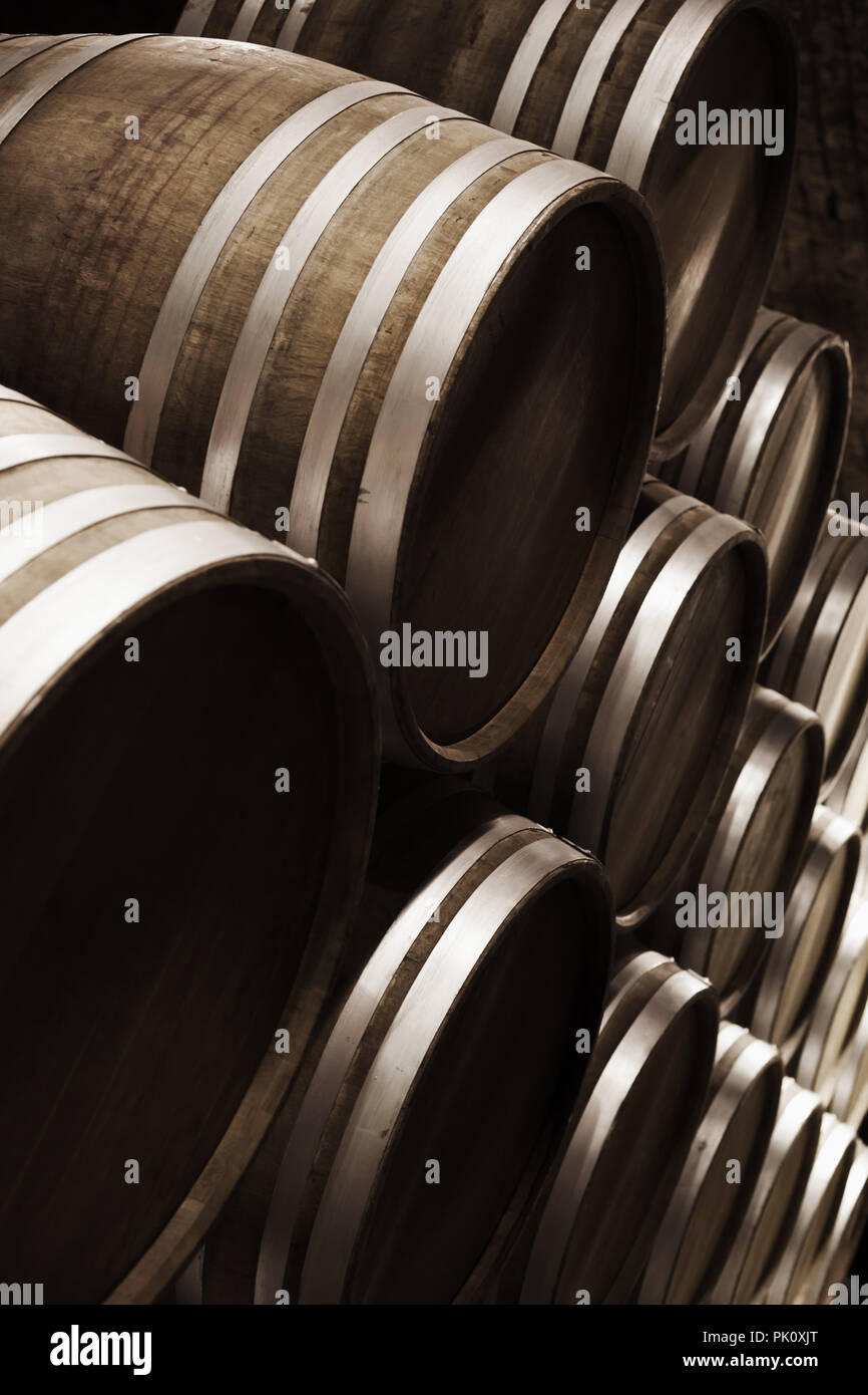 Wine storage. Round wooden barrels in dark winery, close-up vertical photo with selective focus Stock Photo