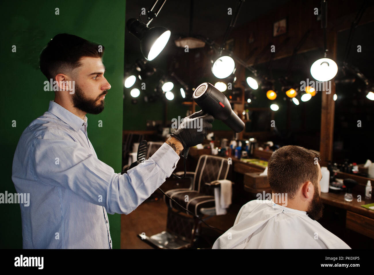 Handsome bearded man at the barbershop, barber at work, using hair ...