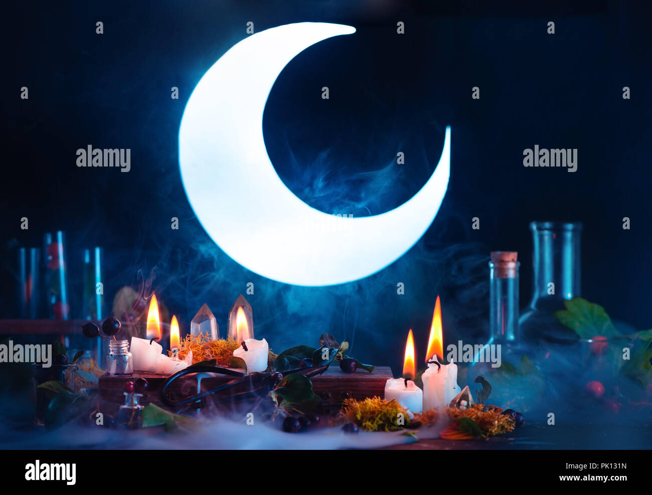 Halloween header with shining full Moon. Witch or wizard workplace with burning candles. Spooky still life concept on a dark background with copy spac Stock Photo