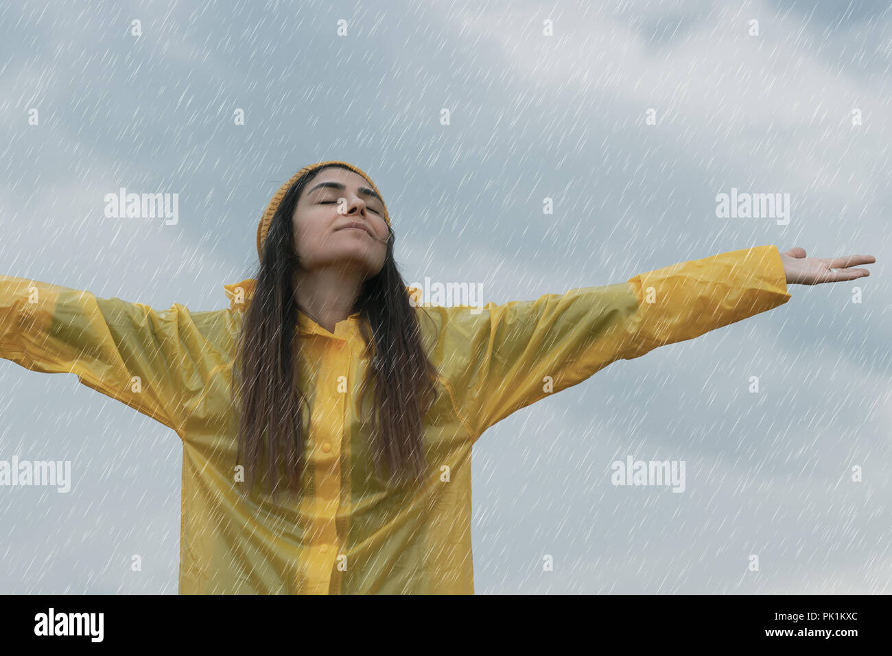Woman wearing yellow raincoat out in the rain Stock Photo