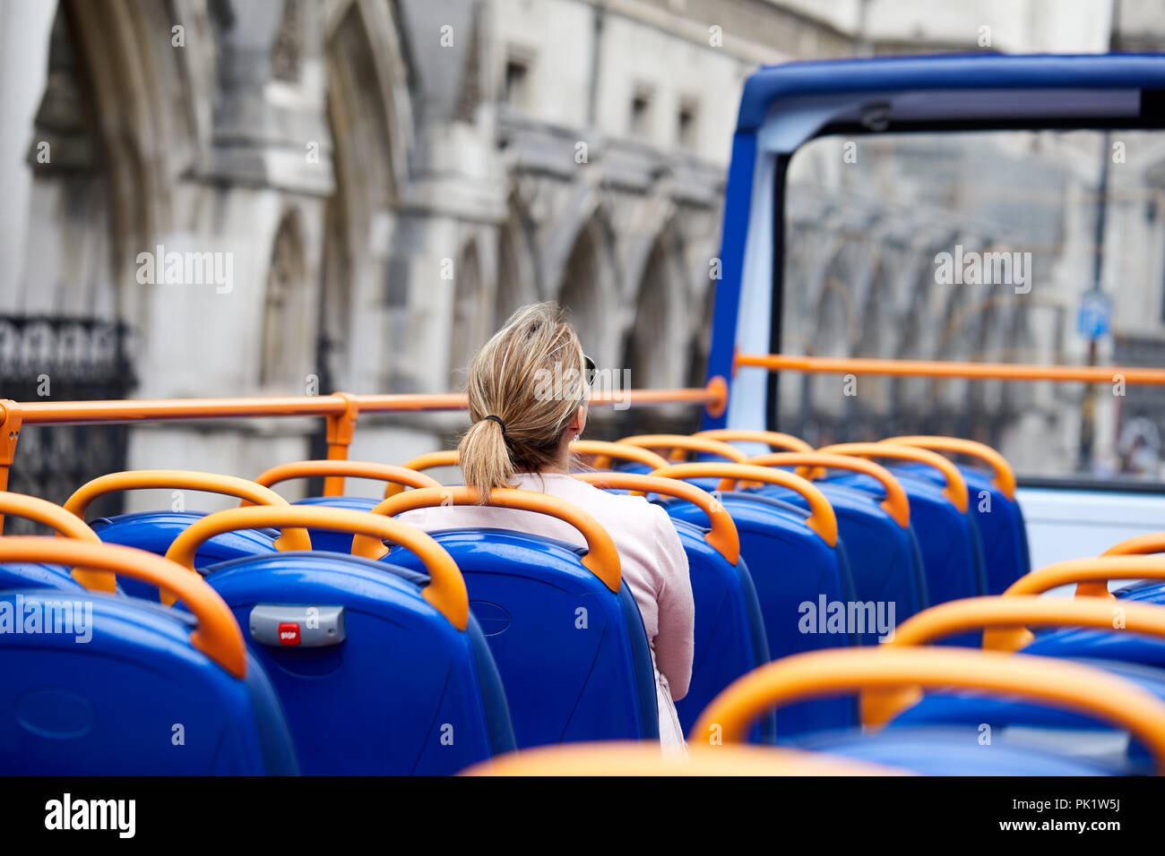A sightseer on a London tourist bus as it passes the Royal Courts of Justice. . Stock Photo