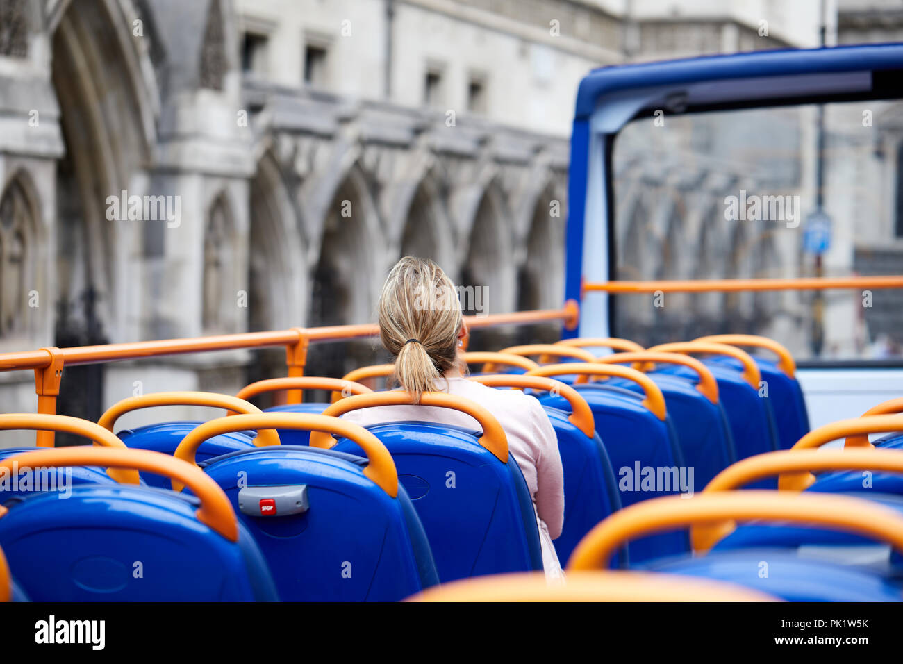 A sightseer on a London tourist bus as it passes the Royal Courts of Justice. . Stock Photo