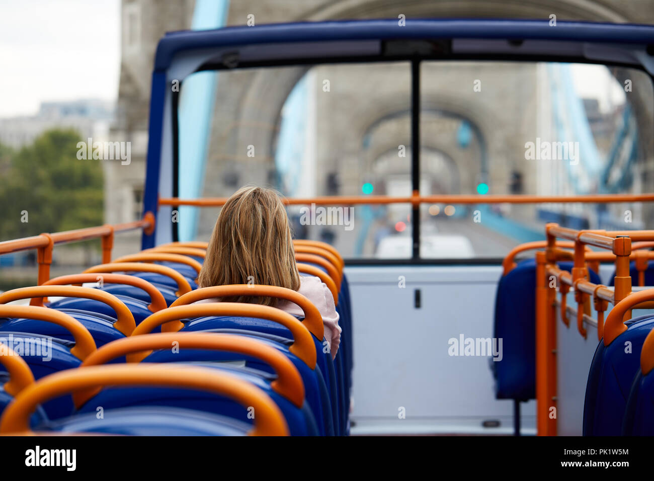 A sightseer on a London tourist bus as it passes over Tower Bridge. Stock Photo