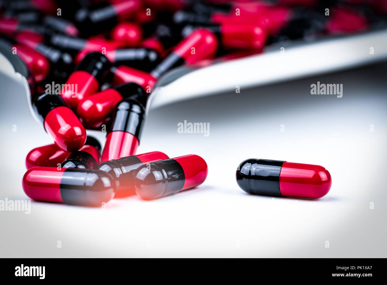 Selective focus of red and black capsule pills on stainless steel drug tray. Antibiotics drug resistance. Global healthcare. Antimicrobial capsule pil Stock Photo