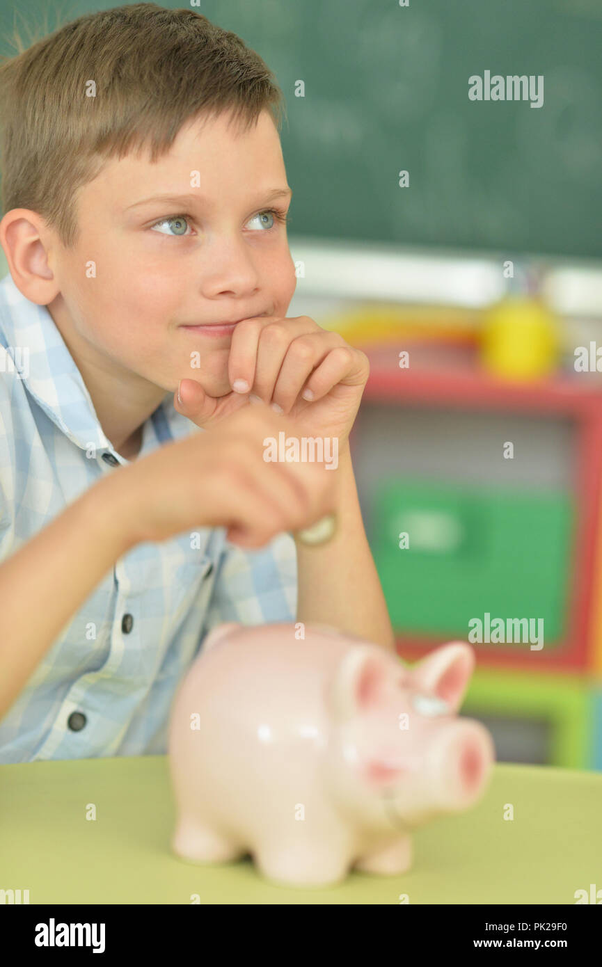 boy putting a coin in a piggy bank Stock Photo - Alamy