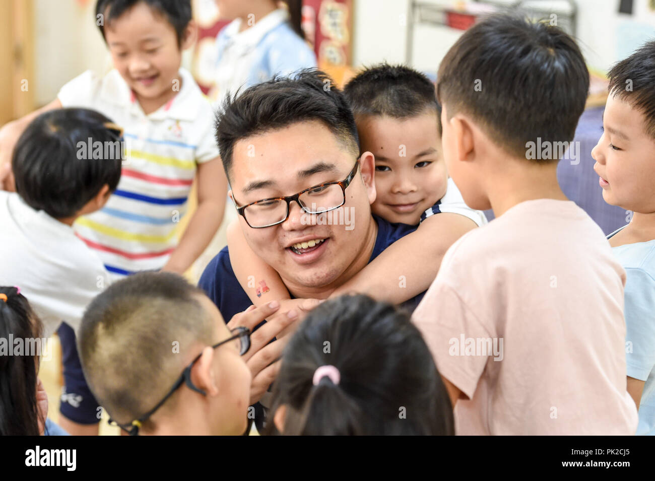 (180910) -- NANJING, Sept. 10, 2018 (Xinhua) -- Guo Xinwang has fun with children at the Xiaoxihu kindergarten in Nanjing, capital of east China's Jiangsu Province, Sept. 4, 2018. Guo, born in 1993 and graduated from the Jiangsu Normal University, became the first and only male teacher of the Xiaoxihu kindergarten three years ago. There are 400 plus male teachers in Nanjing nowadays, up to three percent of the whole teachers working in kindergartens. (Xinhua/Li Bo) (zwx) Stock Photo