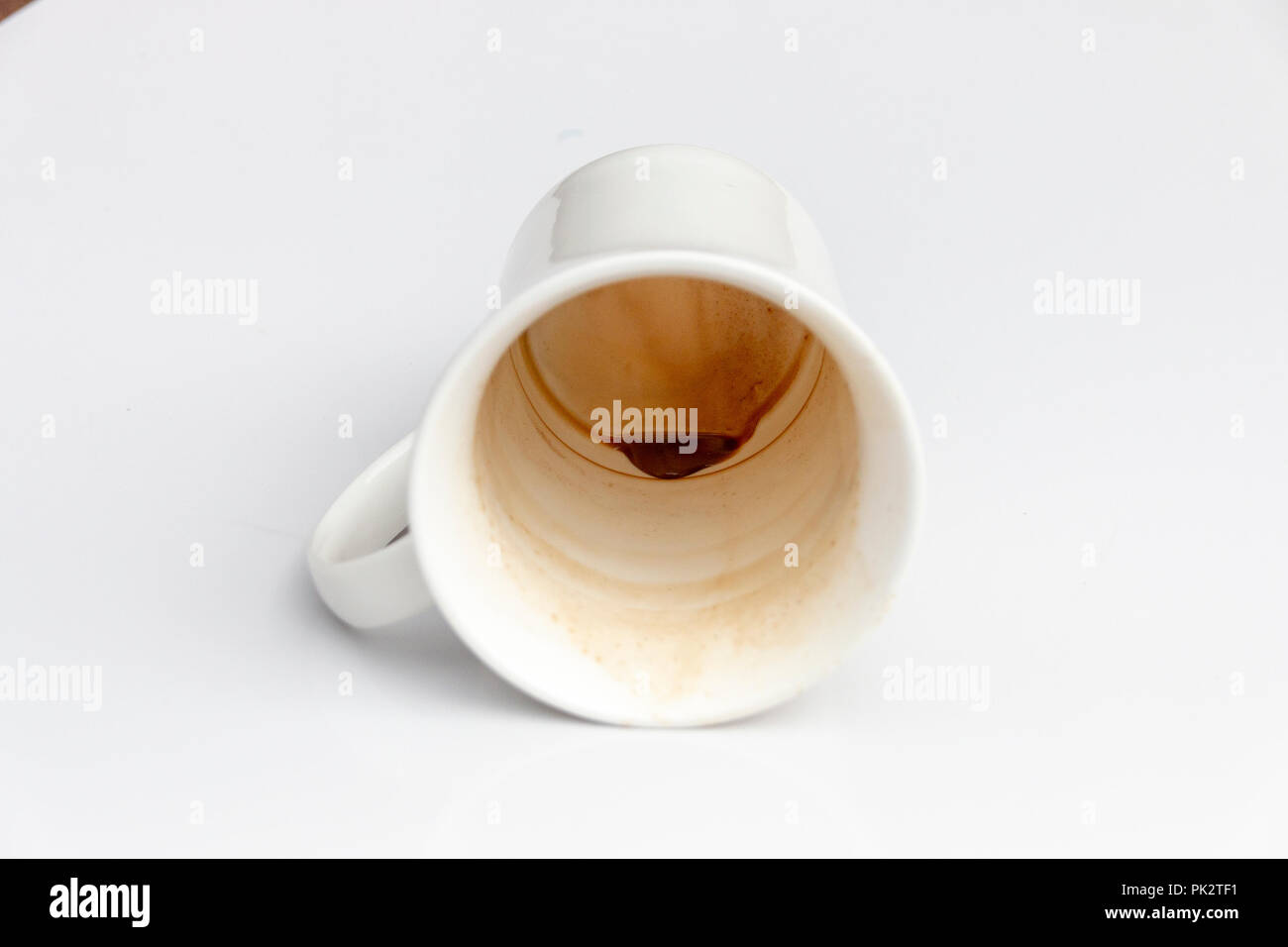 A close up view of a dirty coffee mug on its side on a isolated white