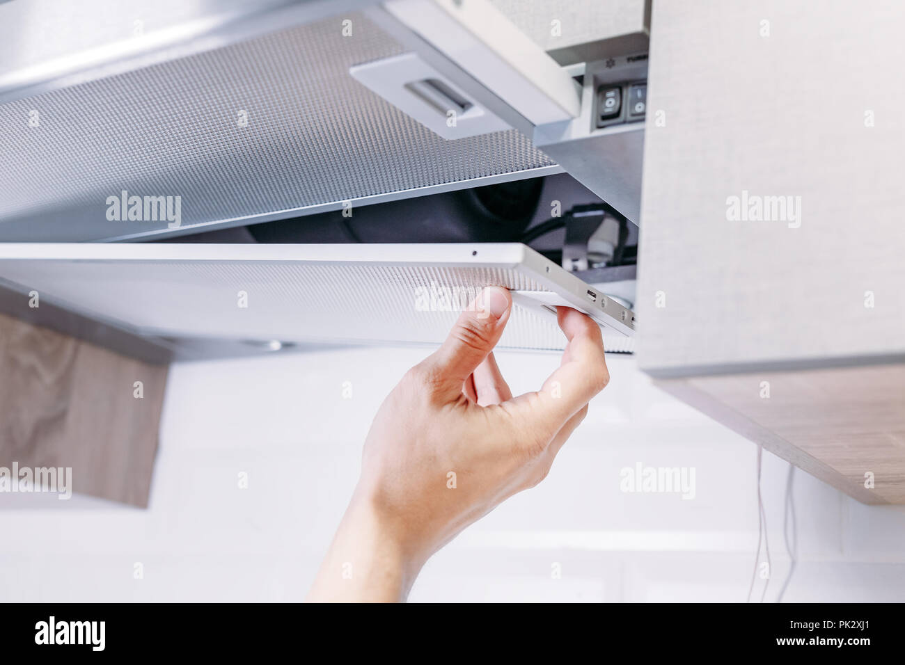 Man repairs hood in the kitchen. Replacement filter in cooker hood