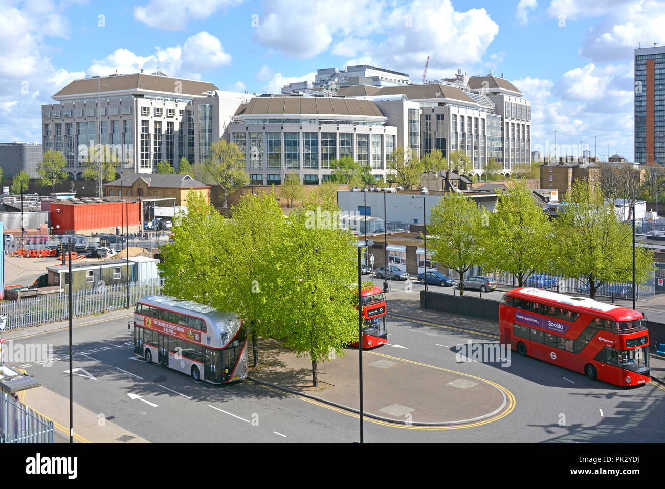 Looking down on London street scene double decker buses wait at bus stop outside Blackwall DLR station Tower Hamlets Council Offices beyond England UK Stock Photo