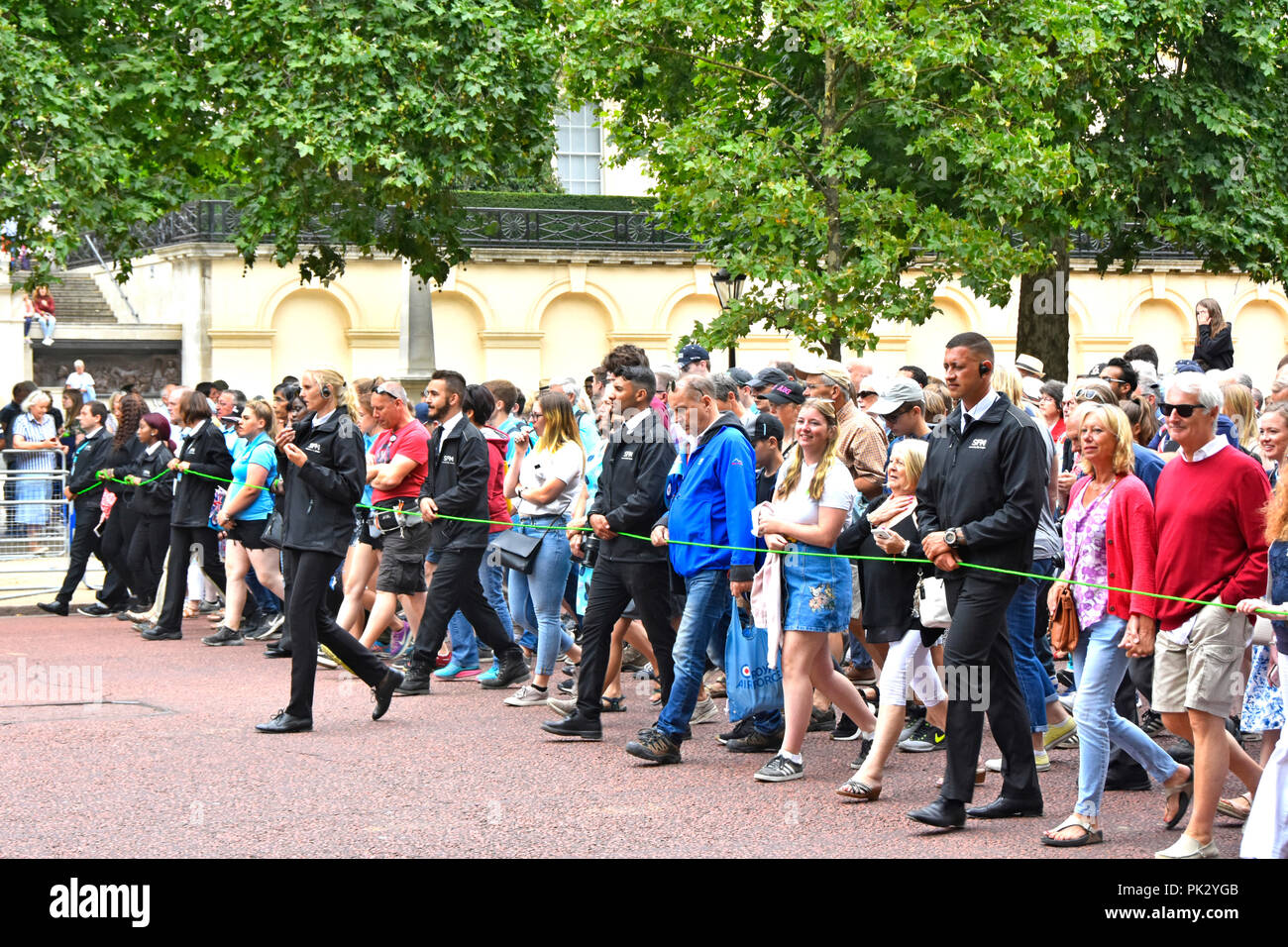 London street scene crowds of people & marshals control group walking The Mall towards Buckingham Palace at RAF centenary parade & flypast England UK Stock Photo