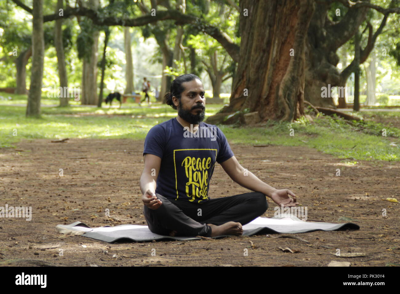 Young Indian in easy pose, sukhasana, at Cubbon Park in bangalore India Stock Photo
