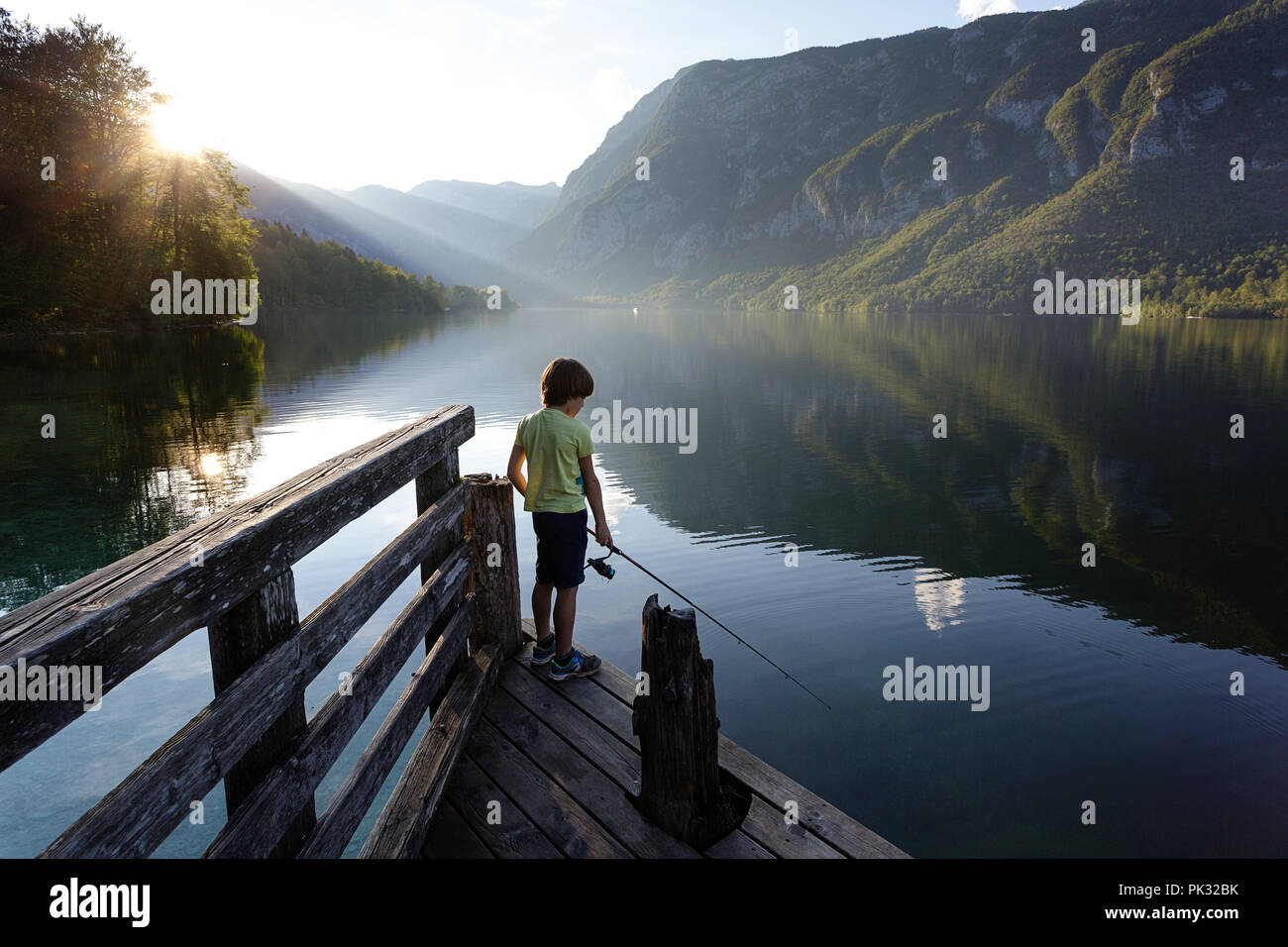 Young boy fishing on pier, lake Bohinj, Slovenia Stock Photo