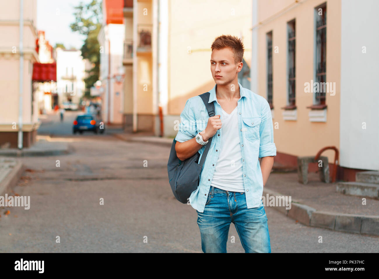 Young handsome man with a backpack in a denim shirt and jeans clothes traveling. Stock Photo