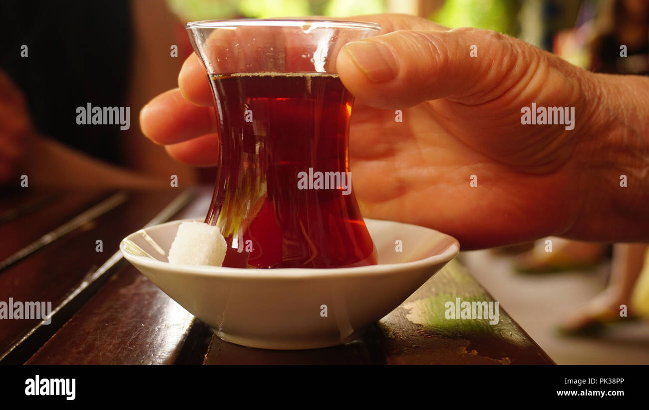 Woman hands are holding a traditional small cup of Turkish black tea Stock Photo