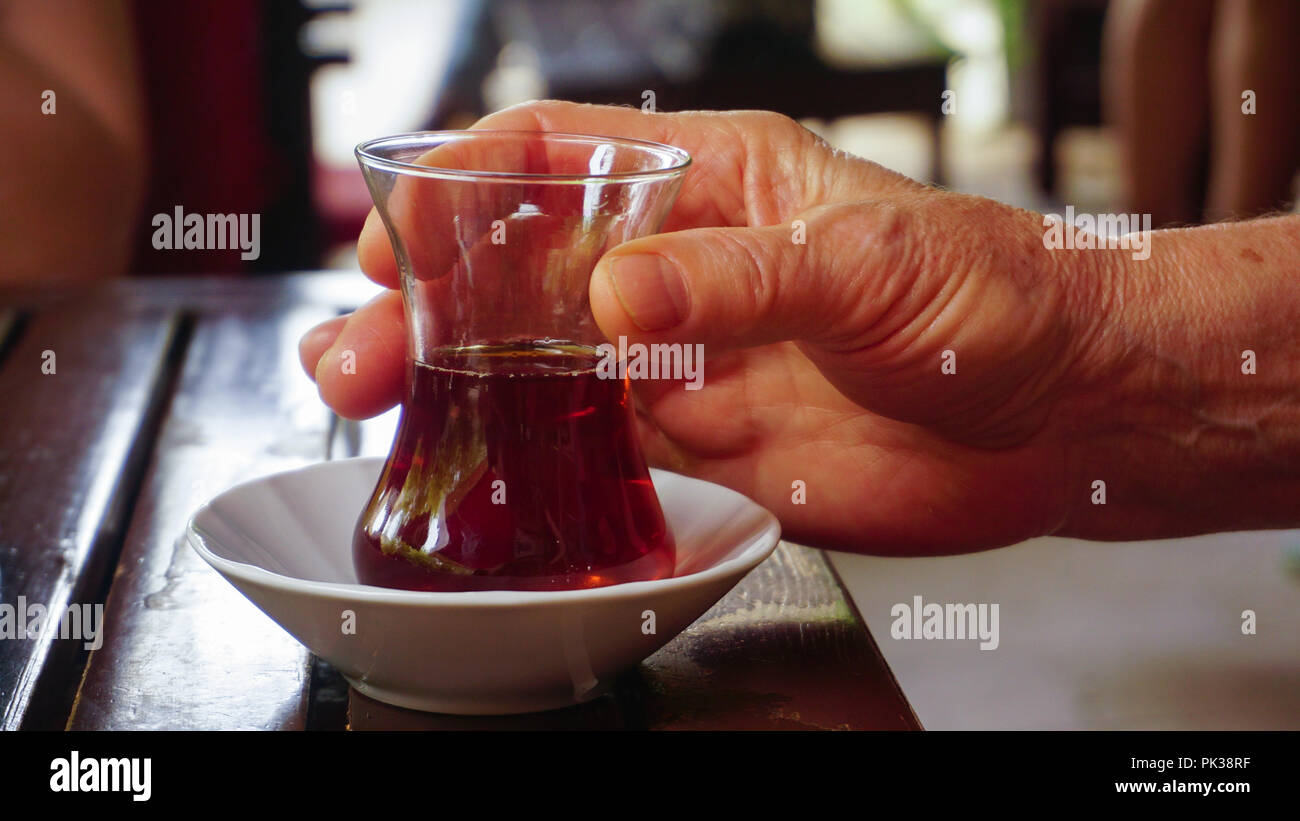 Woman hands are holding a traditional small cup of Turkish black tea Stock Photo
