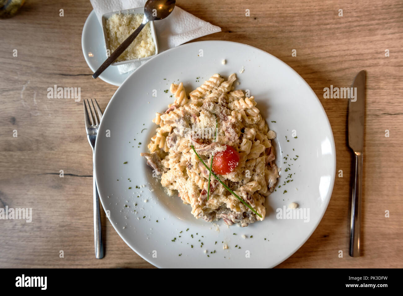 Colorful plate with penne pasta with prosciutto and spinach on a table Stock Photo