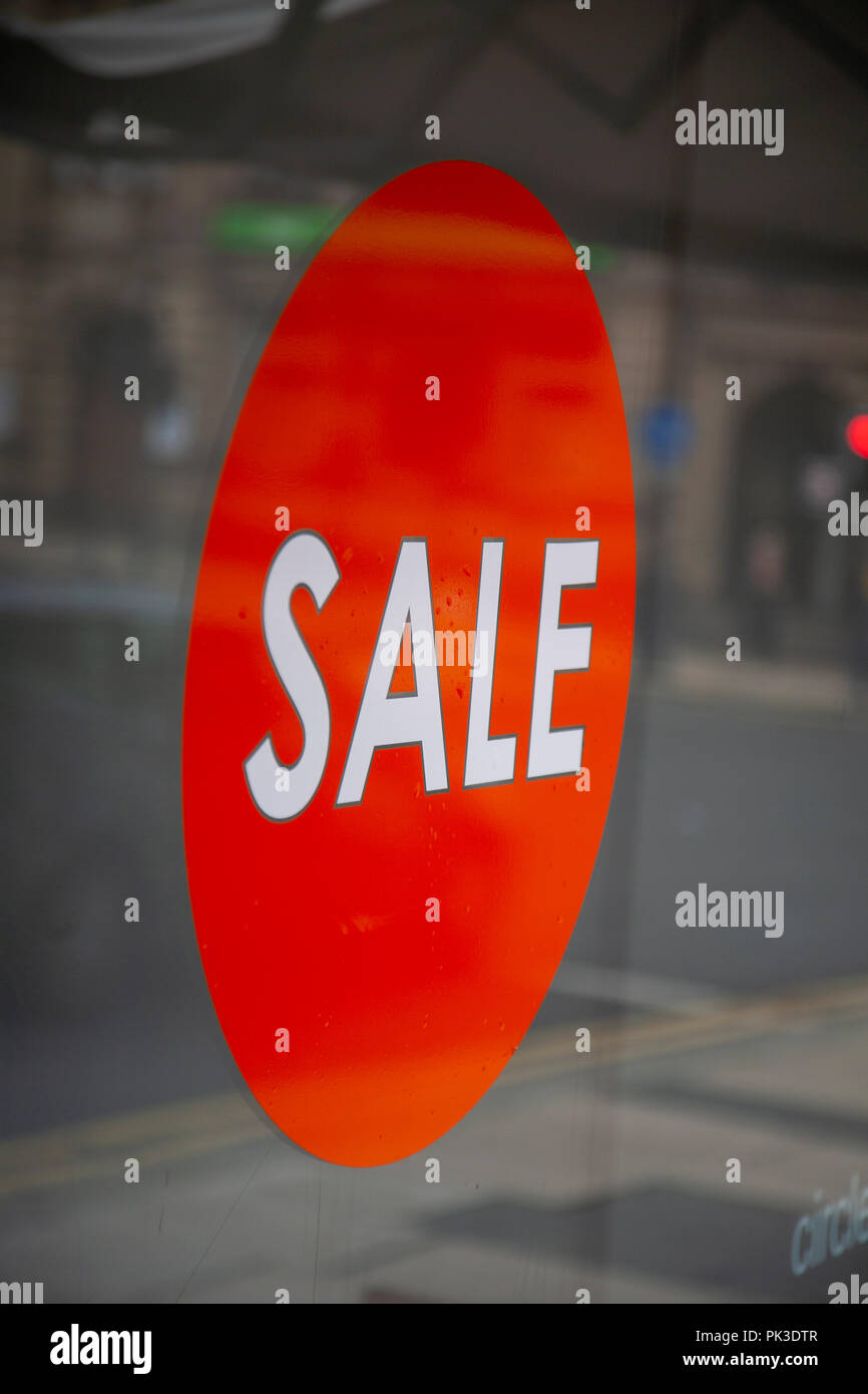 Red circular shop window display sign saying Sale in white lettering in