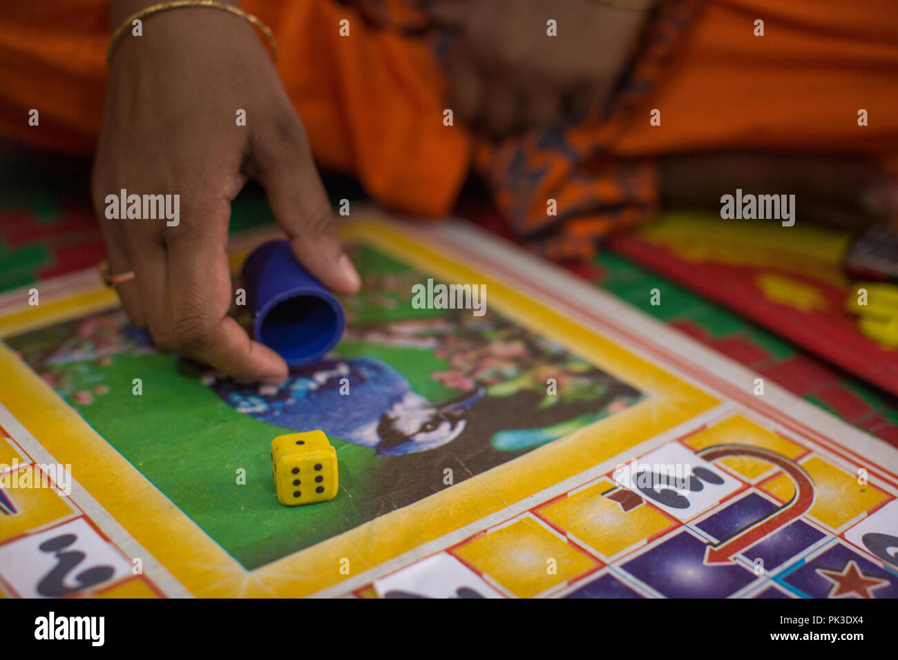 A woman rolling a one on a dice during a board game, Dhaka, Bangladesh. Stock Photo