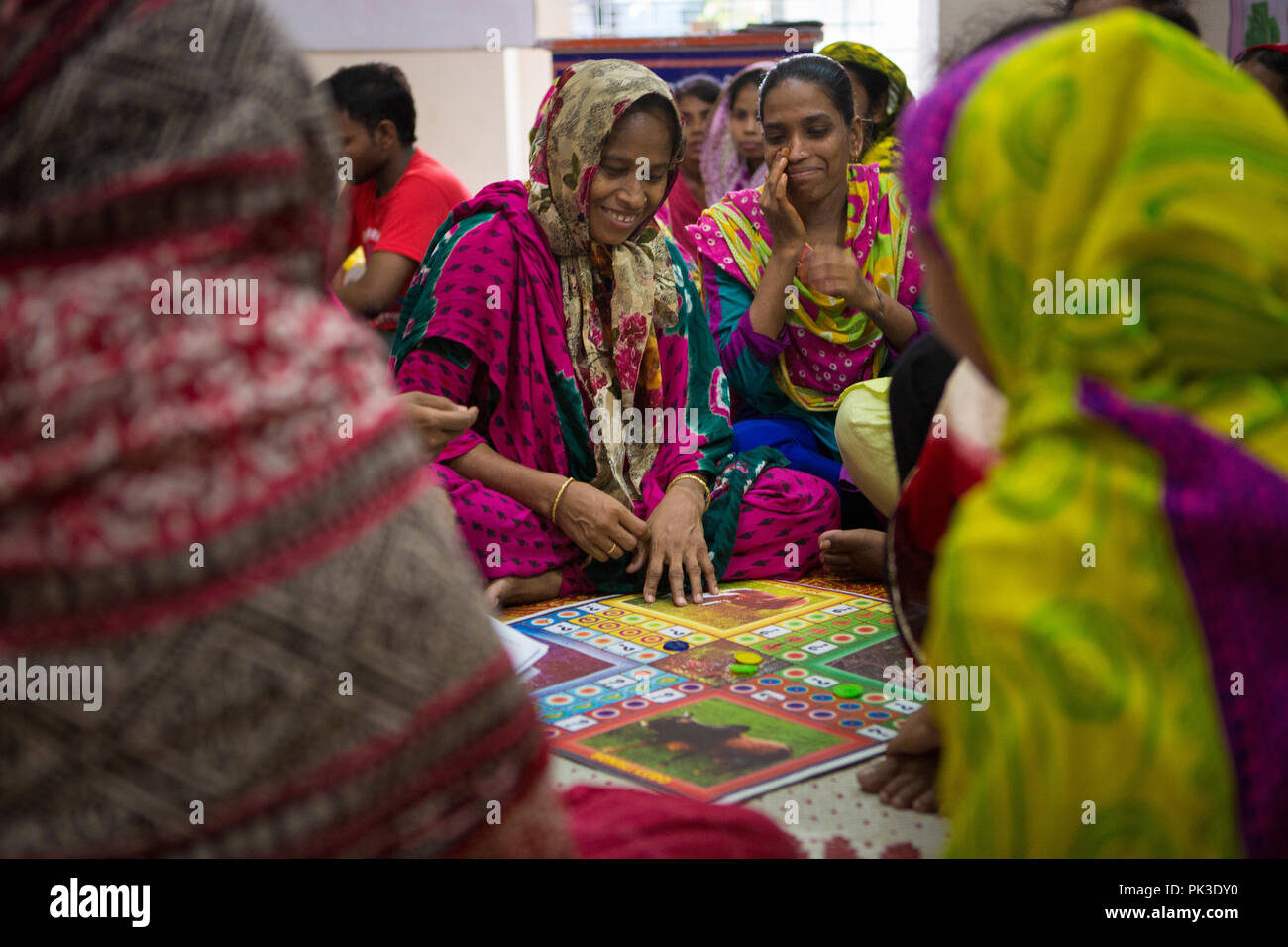 Garment workers laughing as they play a board game during a workshop in Dhaka, Bangladesh. Stock Photo
