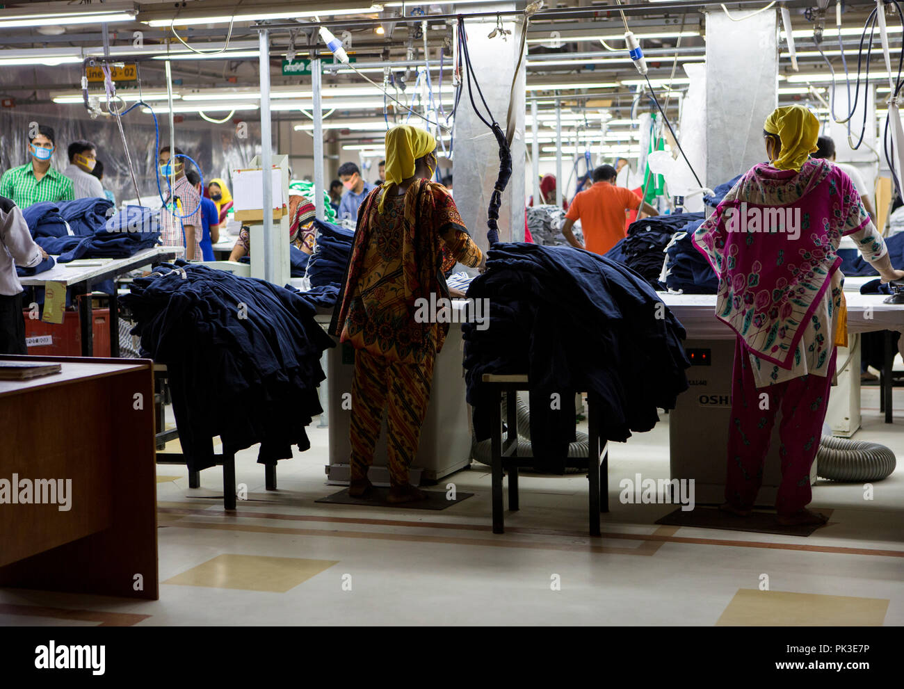 Garment workers ironing clothes inside a garment factory in Bangladesh. Stock Photo