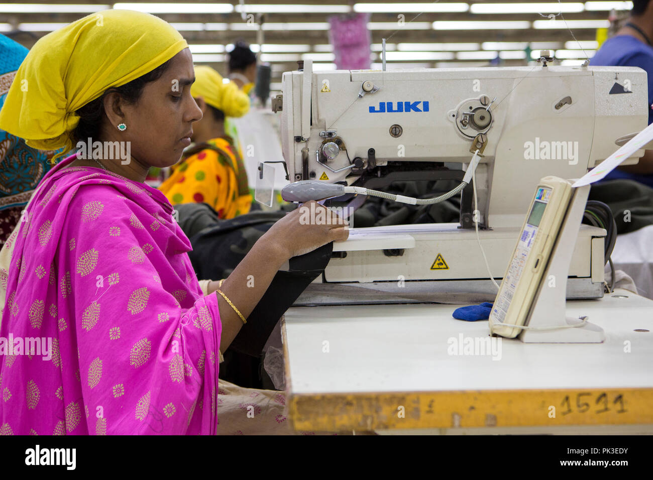 A garment worker at work on a sewing machine inside a garment factory