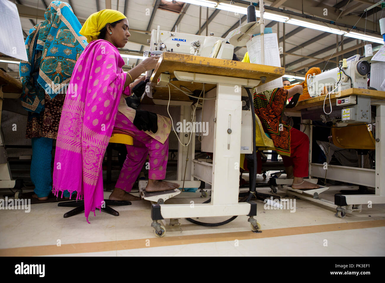 A garment worker at work on a sewing machine inside a garment factory in Bangladesh Stock Photo