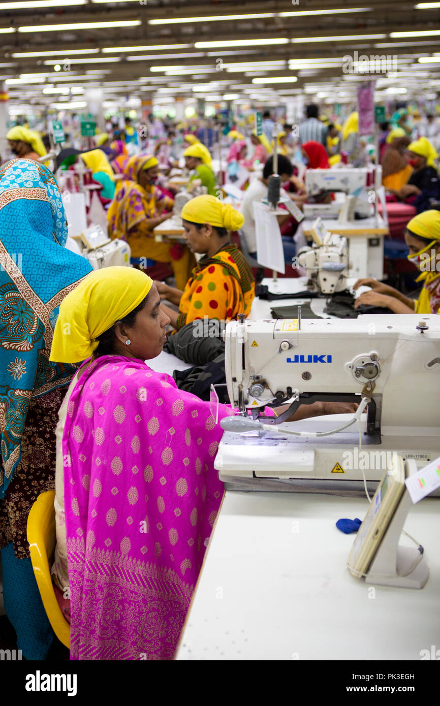 Garment workers at work on sewing machines inside a garment factory in Bangladesh. Stock Photo