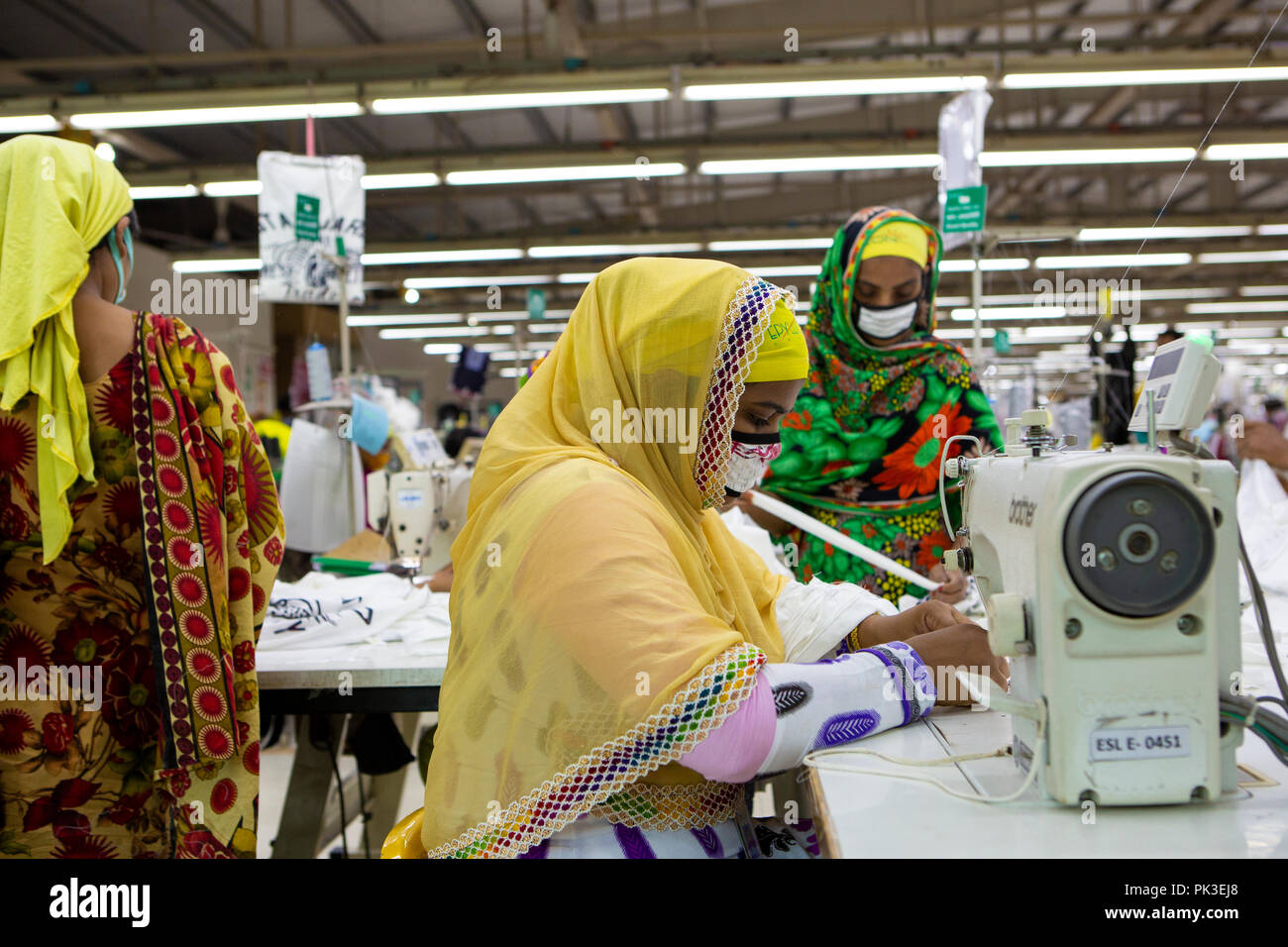 A woman working on a sewing machine at a garment factory in Dhaka