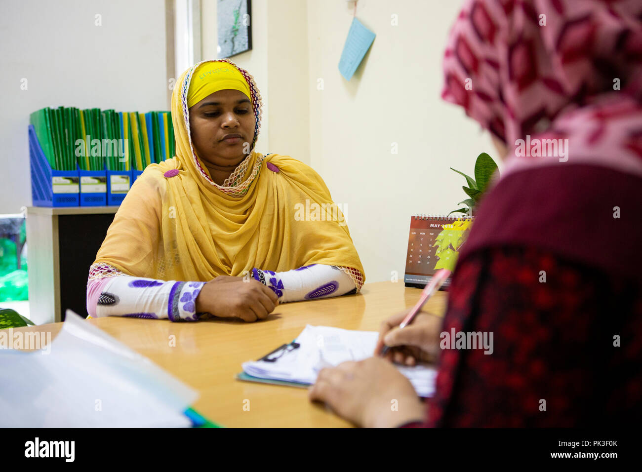 A female garment worker meeting with her manager in garment factory in Bangladesh. Stock Photo