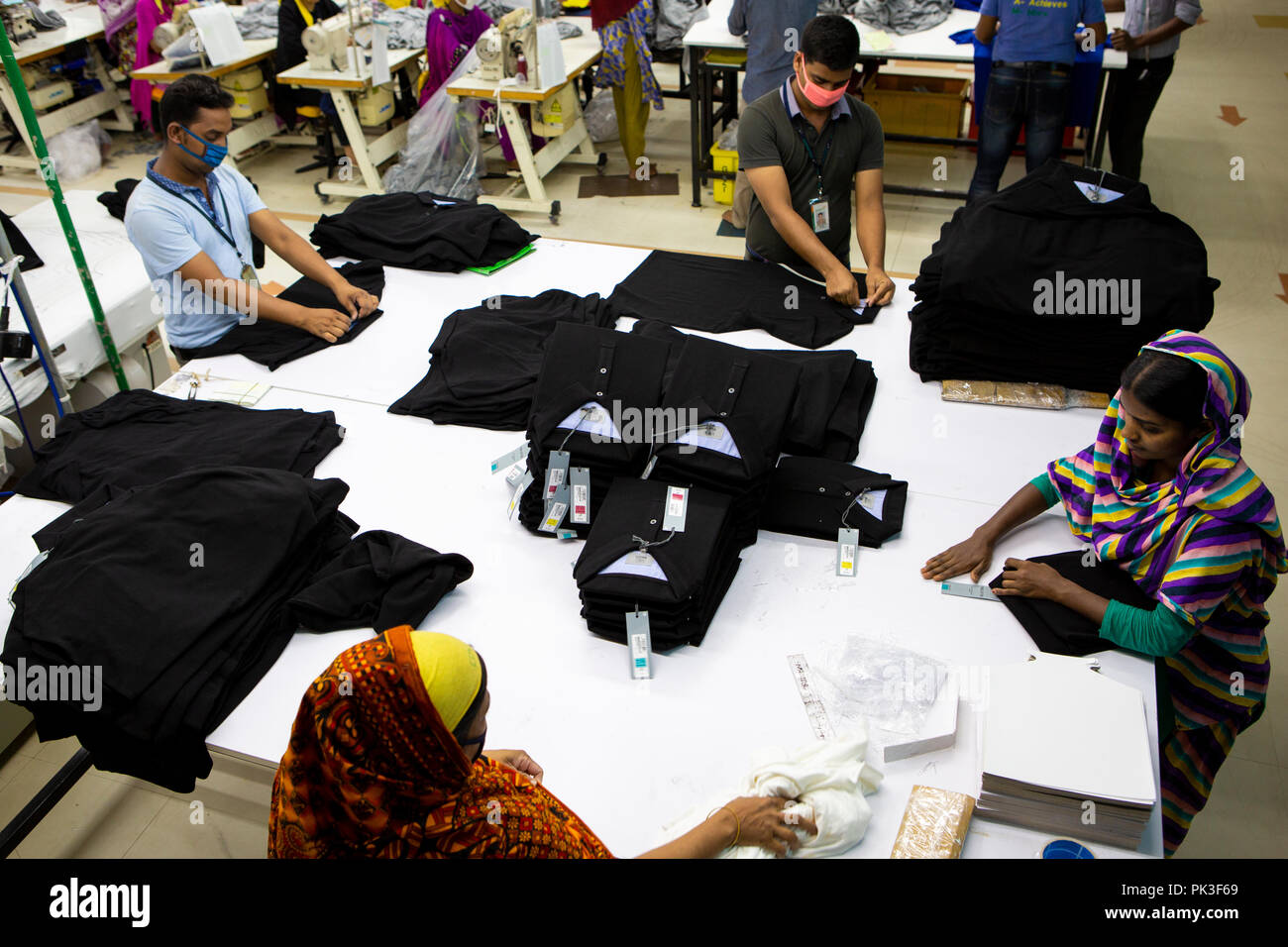 Garment workers folding clothes inside a garment factory in Bangladesh. Stock Photo