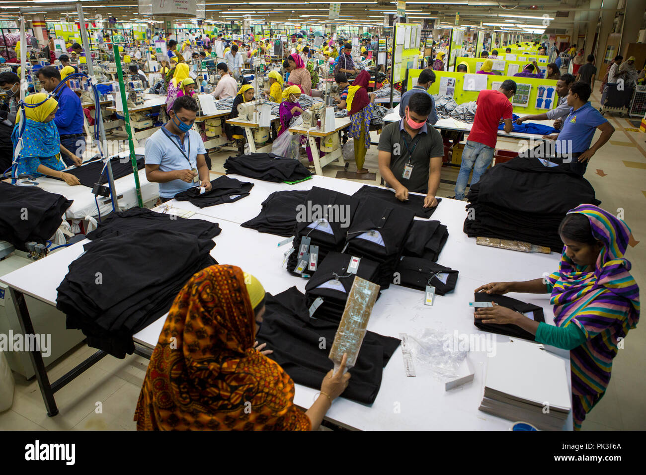 Garment workers folding clothes inside a garment factory in Bangladesh. Stock Photo