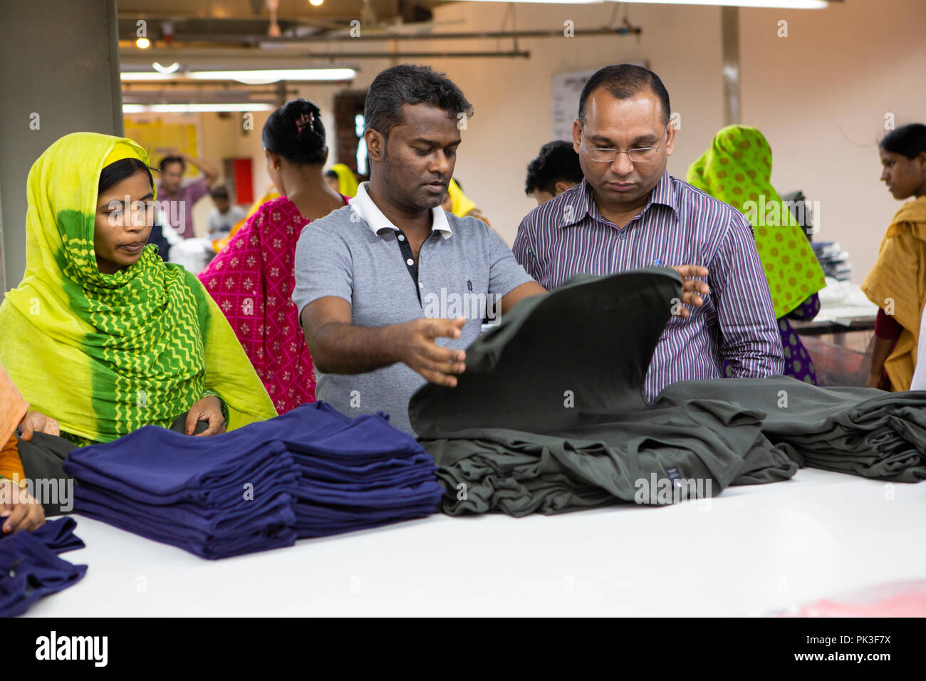 Assistant general manager on the factory floor looking at some of the clothes in production. Stock Photo