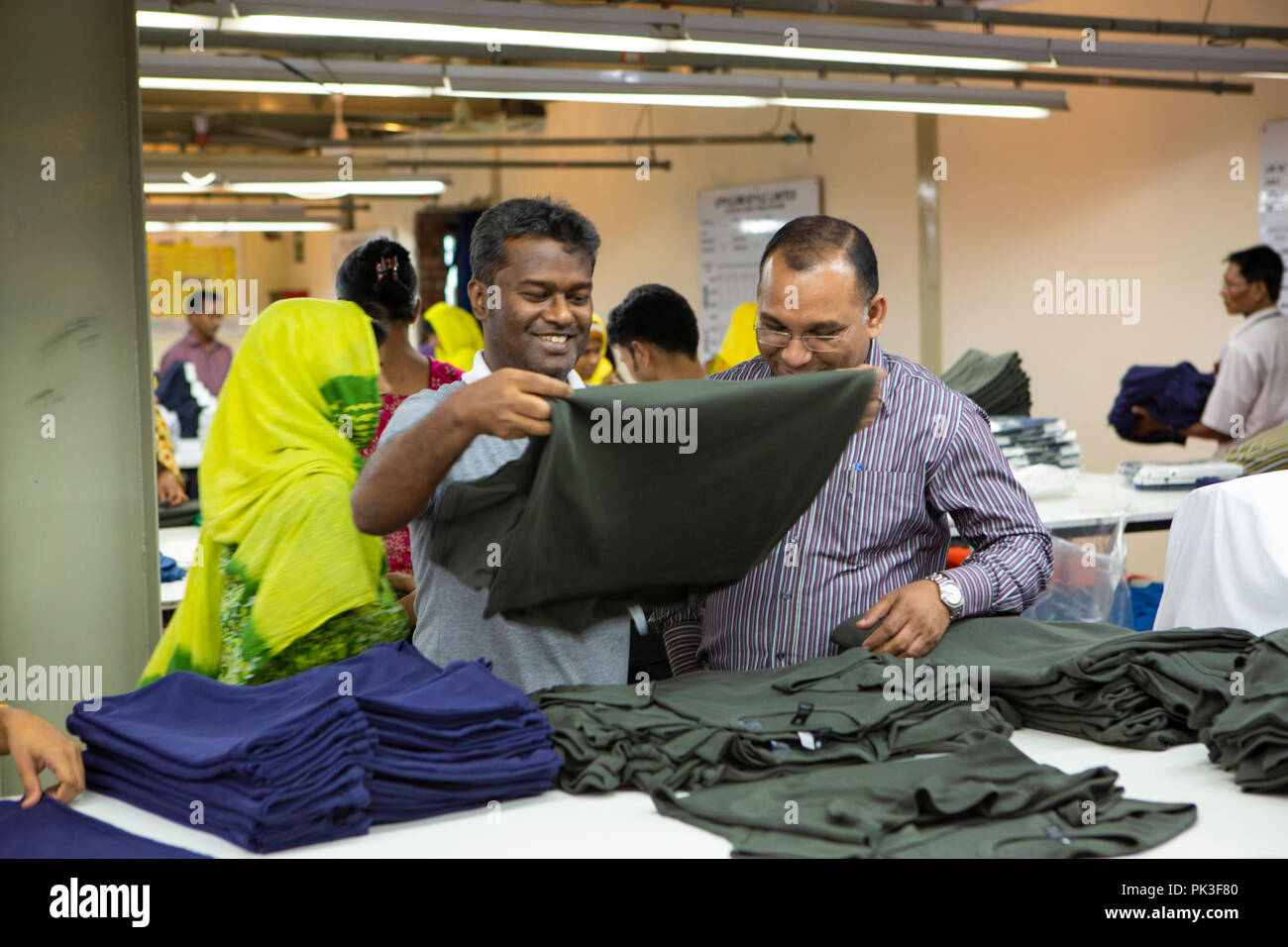 Assistant general manager on the factory floor looking at some of the clothes in production. Stock Photo