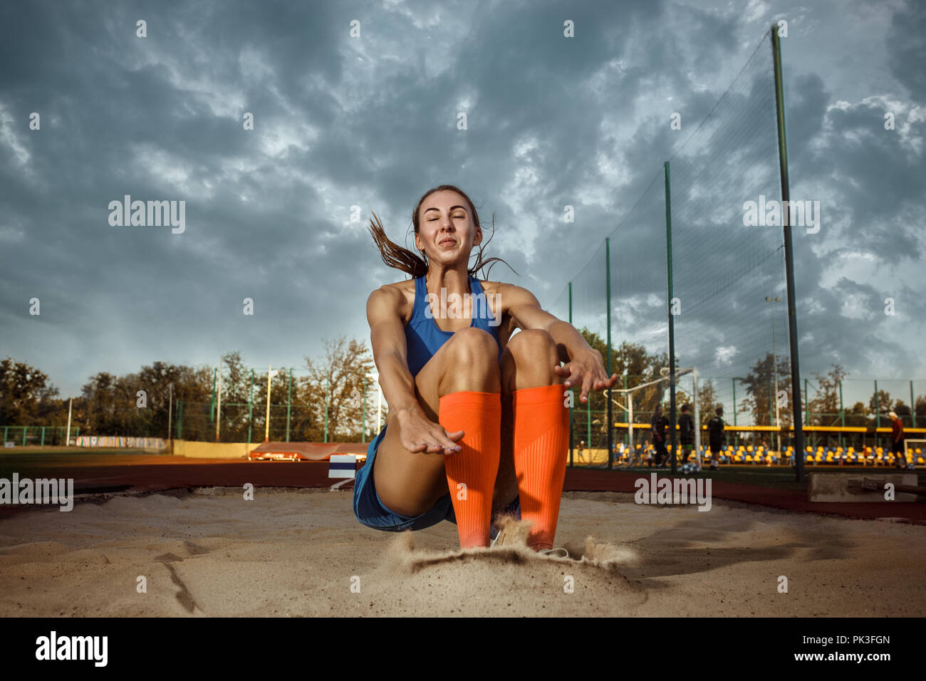Female athlete performing a long jump during a competition at stadium. The jump, athlete, action, motion, sport, success, championship concept Stock Photo