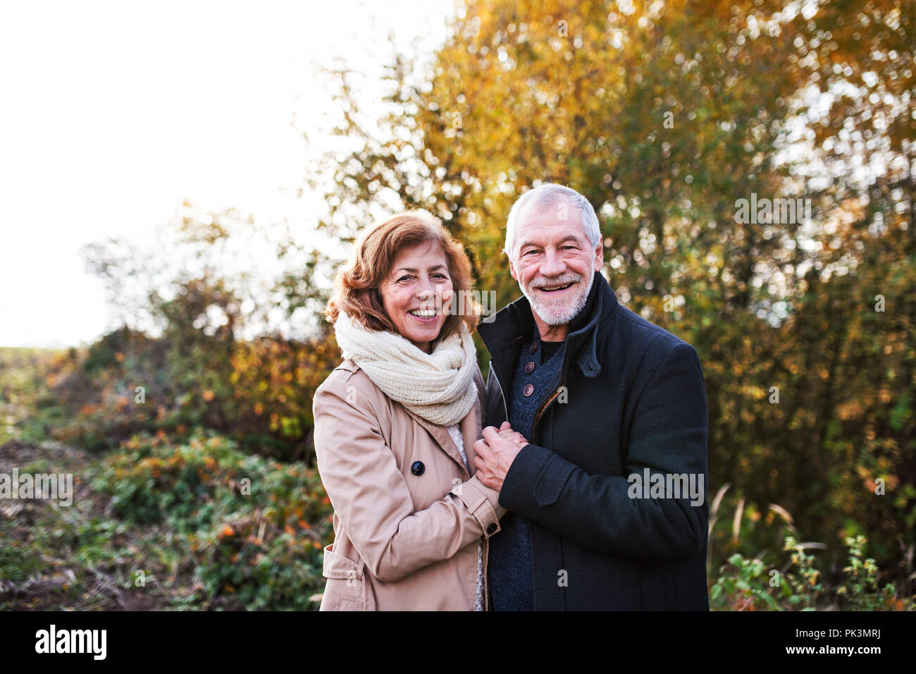 Senior couple standing in an autumn nature, hugging Stock Photo - Alamy