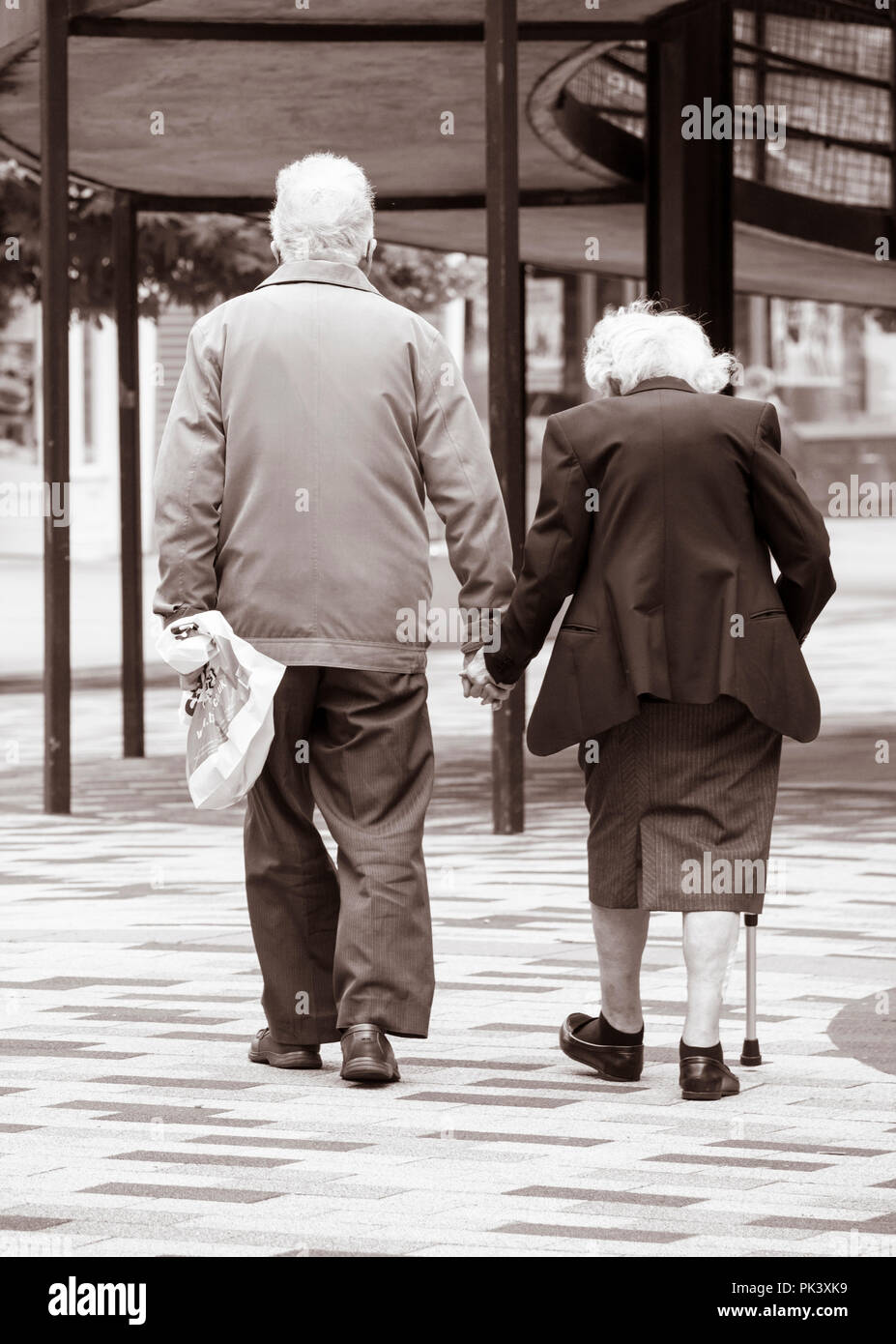 Rear view of eldery couple holding hands. UK Stock Photo