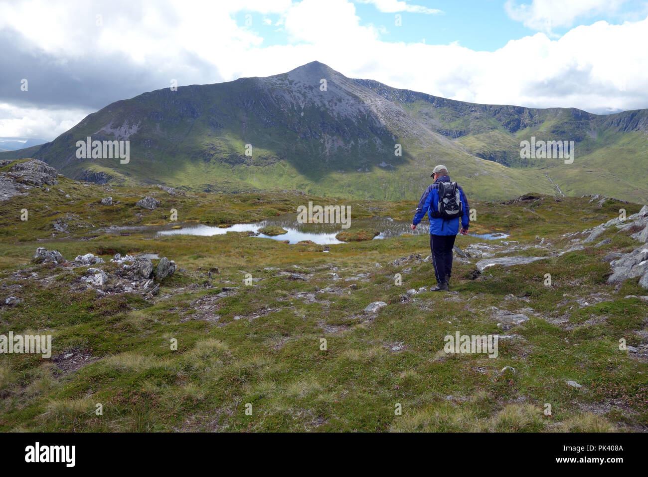 Man Walking on the Corbett Cruach Innse with the Scottish Mountain Stob Coire na Ceannain part of the Grey Corries in front of him in Glen Spean Stock Photo