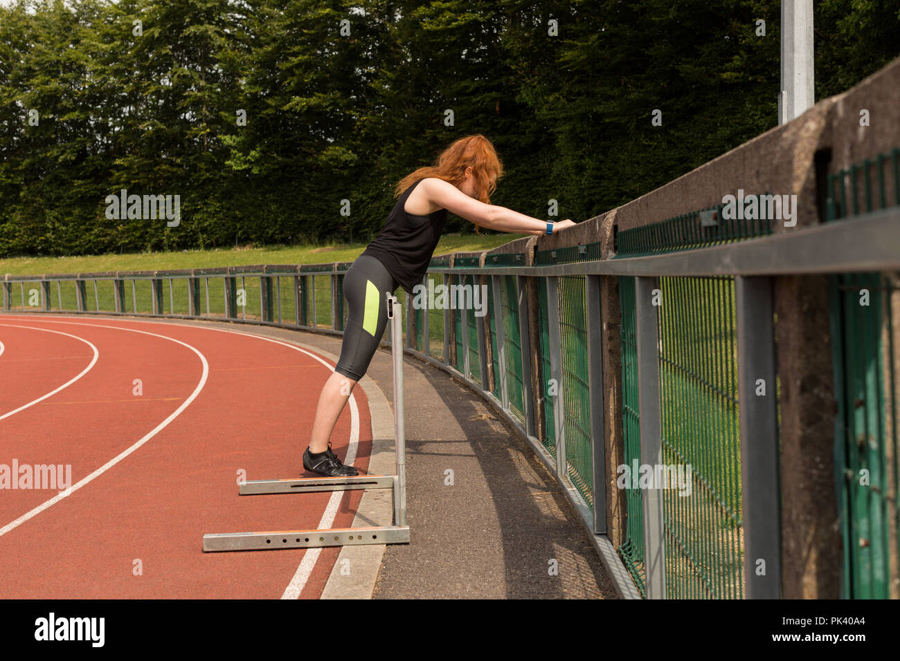 Female athlete exercising on railing at sports track Stock Photo