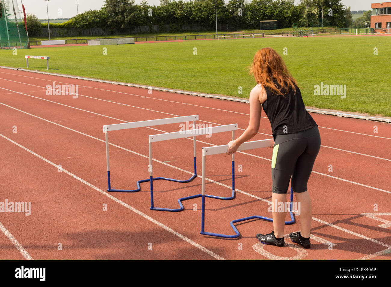 Female athlete arranging hurdles on running track Stock Photo