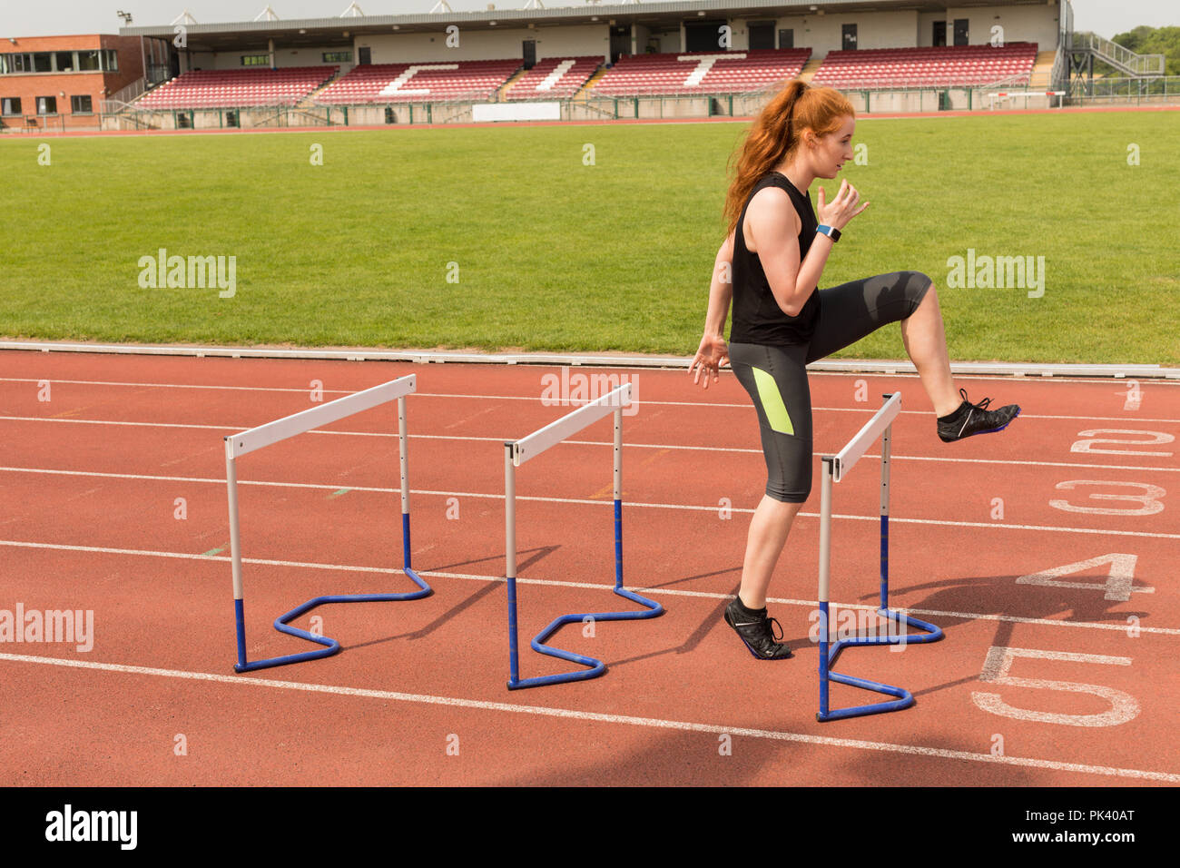 Female athlete exercising over hurdles Stock Photo