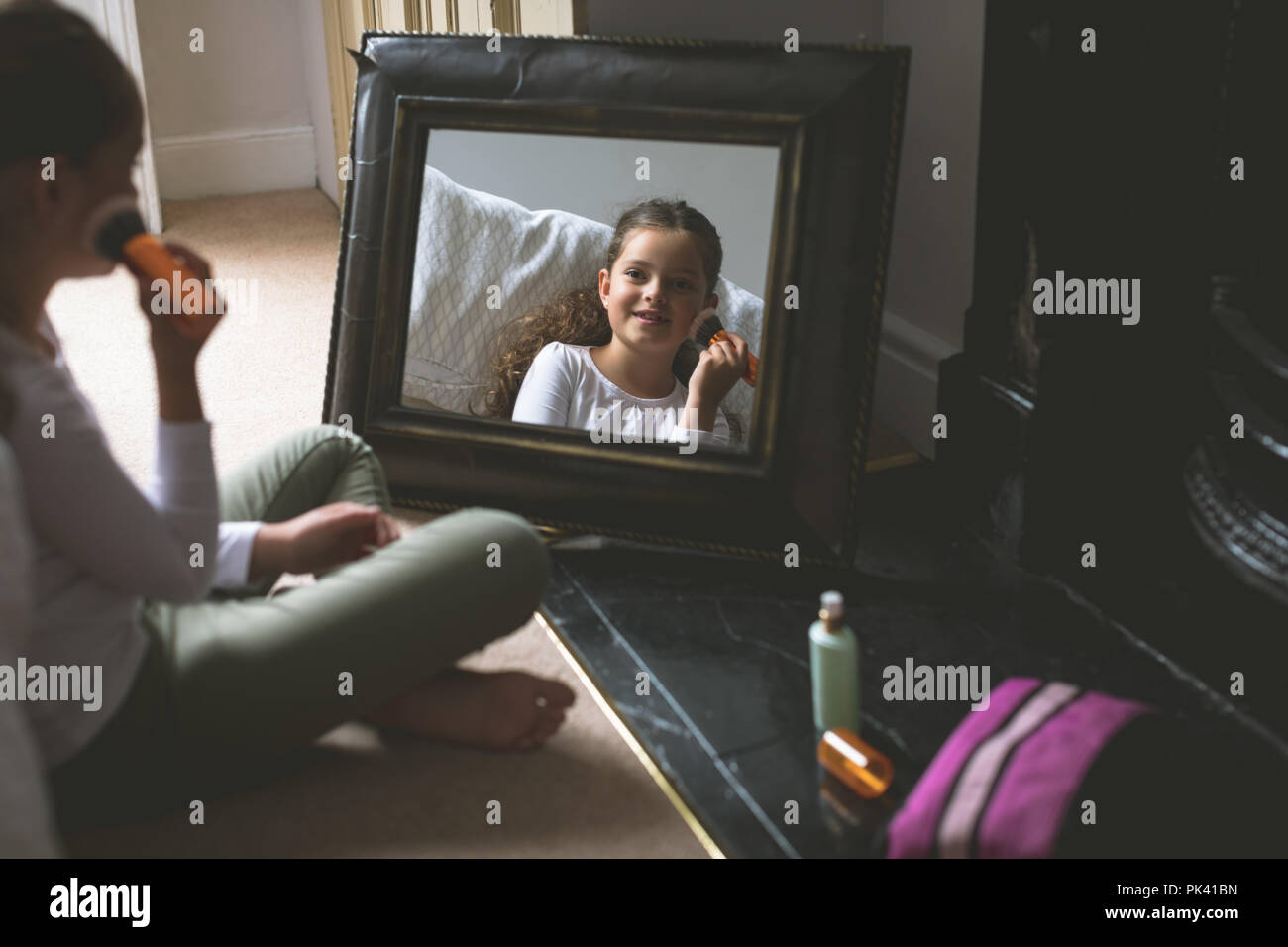 Girl applying makeup in front of mirror Stock Photo