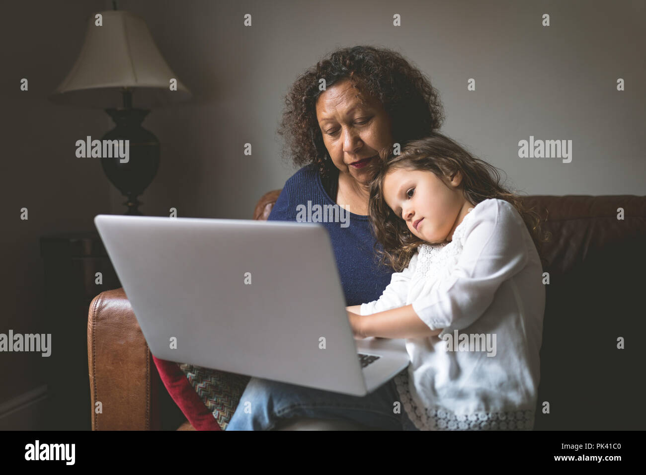 Little girl using laptop with grandmother on sofa Stock Photo - Alamy