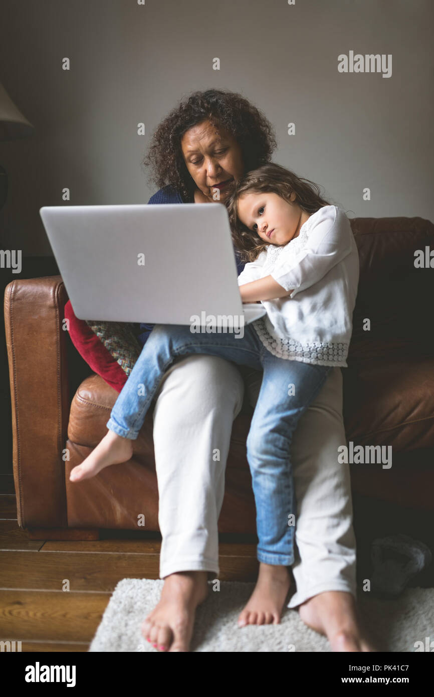 Little girl using laptop with grandmother on sofa Stock Photo - Alamy