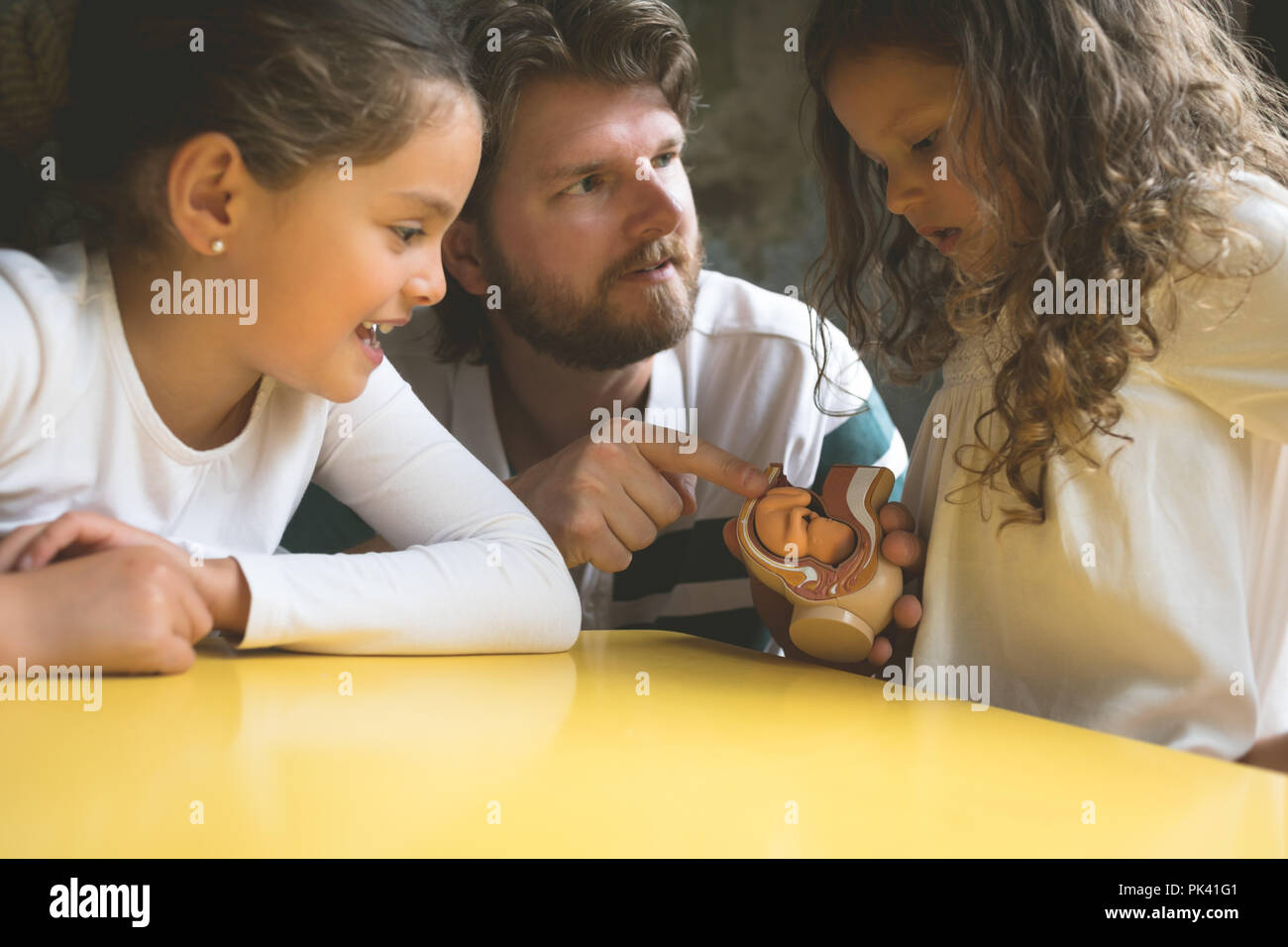 Father explaining his daughters about fetus model Stock Photo