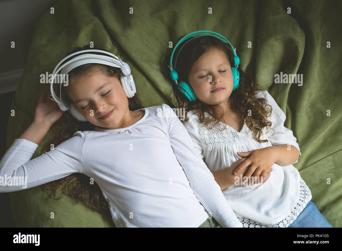 Siblings listening music while relaxing in bedroom Stock Photo