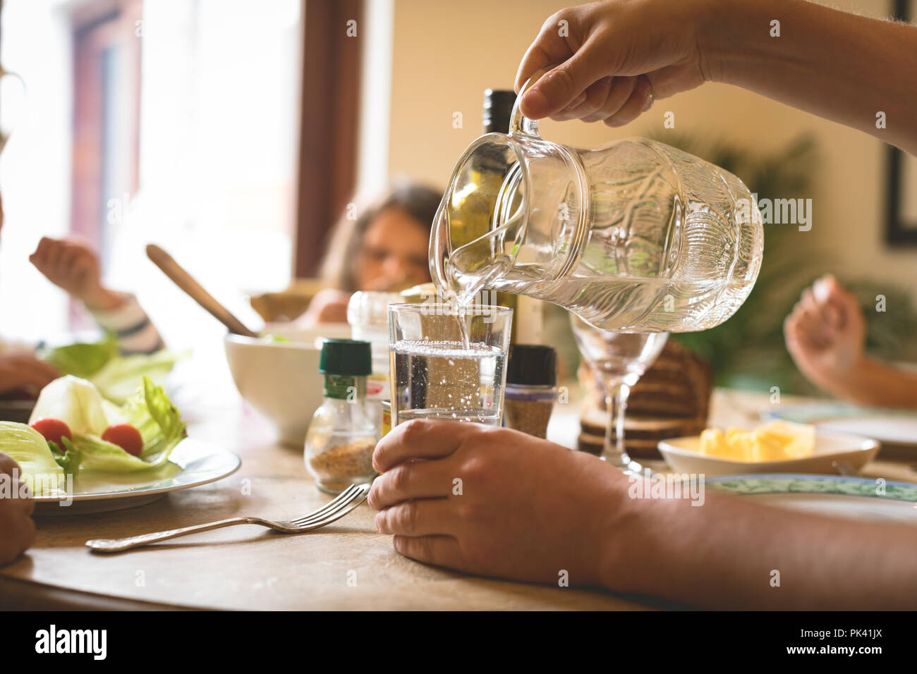 Man serving water in glass on dining table Stock Photo