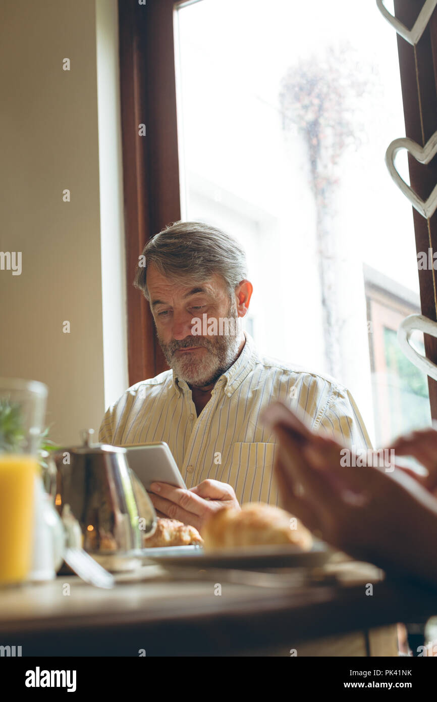 Senior man using digital tablet while having breakfast Stock Photo