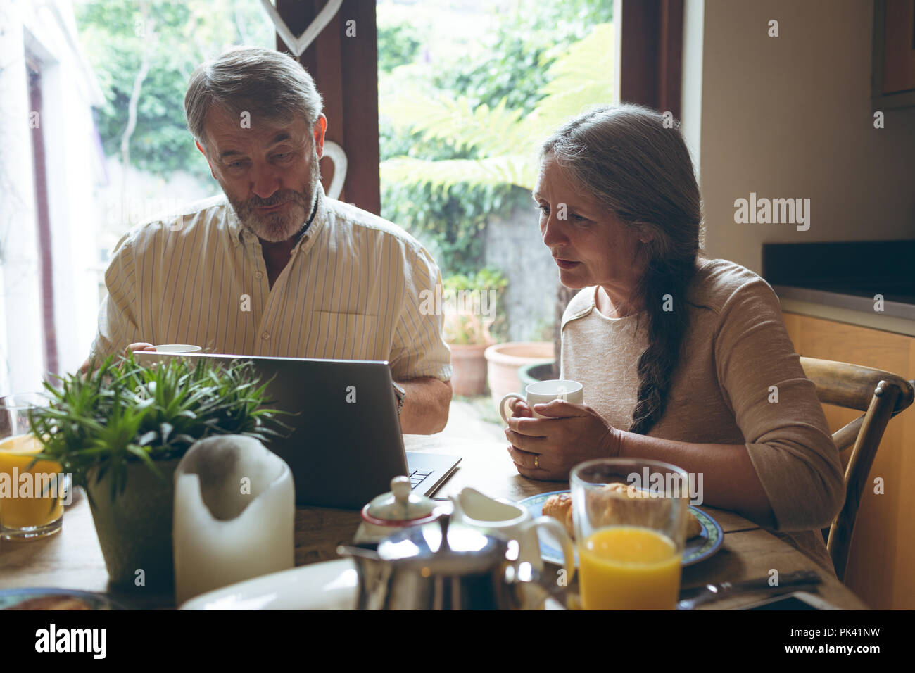 Senior couple using laptop while having coffee Stock Photo