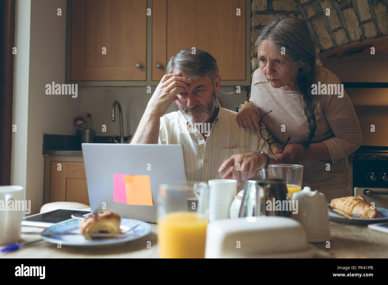 Senior couple using laptop on dining table Stock Photo