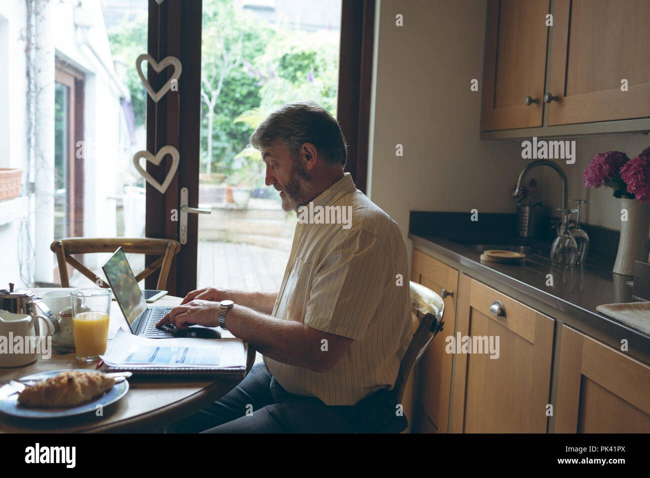 Senior man using digital tablet on dining tablet at home Stock Photo
